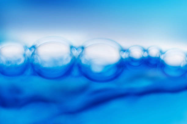 Many air bubbles popping up on water surface of sea with clean water on summer day in nature against blue sky