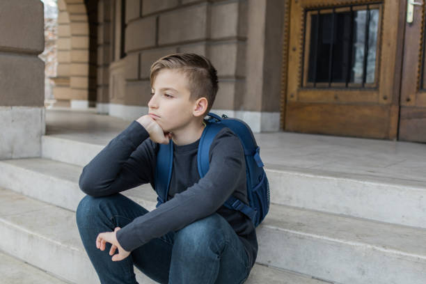 istock Schoolboy with backpack is sitting on staircase near the school building on first school day. Back to school. Education. 2140202097