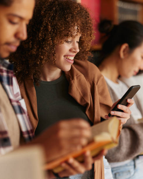 istock Happy female student text messaging on mobile phone in library. 2140261803