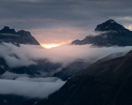 A dramatic sunset over mountains shrouded in clouds