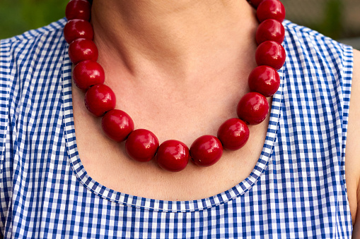 Necklace with red beads around the neck of a woman