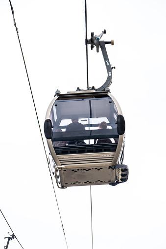 A family enjoying aerial views inside a Vilanova de Gaia cable car gondola suspended on the hanging steel cables under a cloudy white sky in Porto.