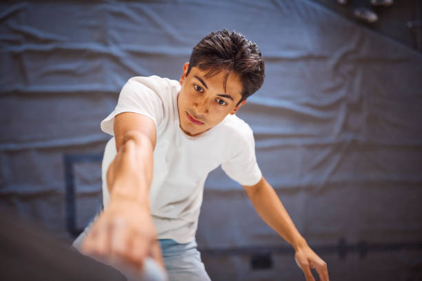 Close Up Of Determined Man Tackling Climbing Wall At Indoor Activity Centre
