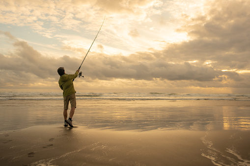 A retired fisherman surf casting at Muriwai Beach