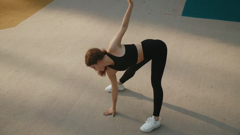 A woman in sportswear is performing a yoga pose on the gym floor