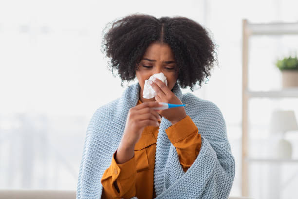 istock Distraught woman with curly hair checking her temperature with a thermometer 2140345534