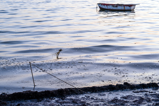 sea ​​pollution, blackness washed ashore, boat tied to shore