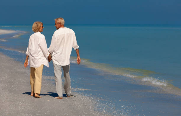 istock Happy Senior Couple Walking Smiling on a Beach 2140354050