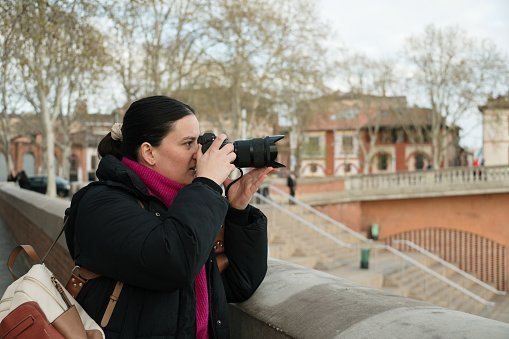 A young woman taking a photo with a professional DSLR camera