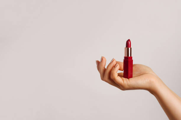 istock Woman hand holding red lipstick on light background, copy space 2140372008