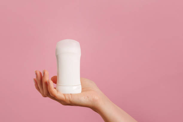 istock Female hand holding white deodorant on pink background. Closeup. copy space 2140372011