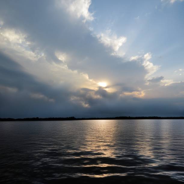 A serene lake under a cloudy sky with sunbeams. Lake Conroe, Texas