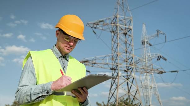 istock Power line inspector making notes during inspection of transmission towers 2140374735