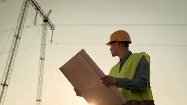 istock Energy auditor consulting blueprints during transmission tower inspection 2140374767