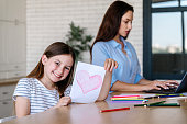 Happy kid holding handmade postcard with red heart drawing with pencil