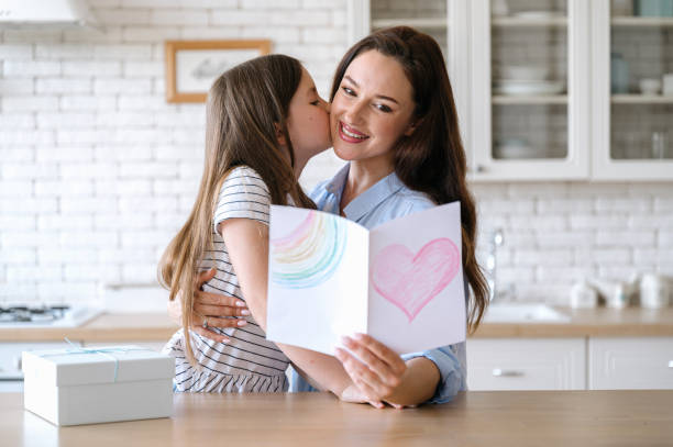istock Happy smiling mother hugging daughter and holding handmade postcard 2140417153