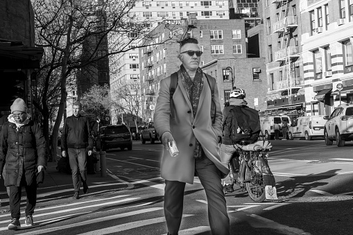 Manhattan, New York, USA - March, 2024. Locals walking on a crosswalk in Manhattan.  In the foreground is a businessman walking to work.