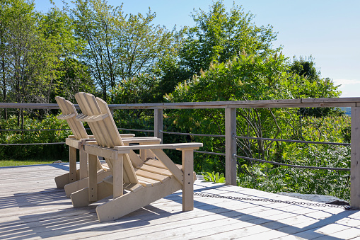 A scenic wooden deck with chair, surrounded by trees and mountains