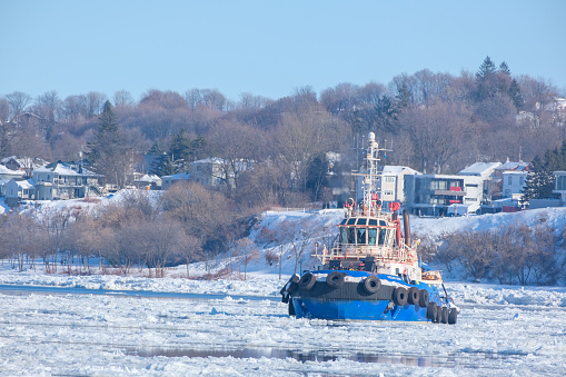 A boat rests on ice near distant buildings