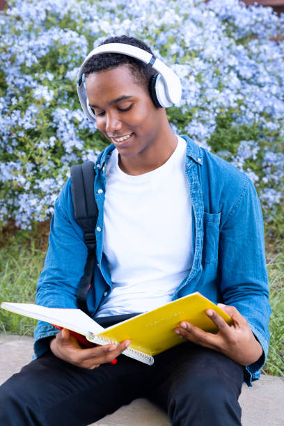 istock Smiling young African American man looking at class notes outdoors. Vertical 2140428933