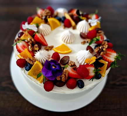 white cream cake with spirals and scalloped sides. fruit and flowers and cinnamon cure as a declaration of summer style
