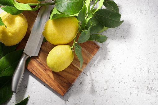 Close up of some lemons on a chopping board on a kitchen countertop