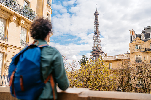 Handsome young man looking at view of an Eiffel Tower from the street in Paris in France.