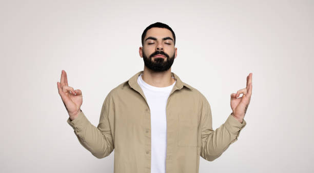 istock A man with a beard and closed eyes raises both index fingers upwards 2140480300