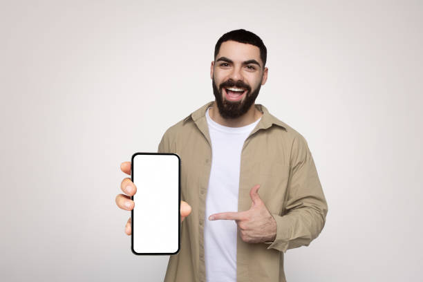 istock Cheerful man with a beard, happily presenting a smartphone with a blank screen 2140480860