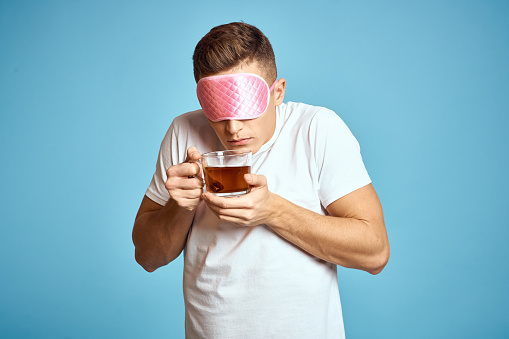 man with pink sleep mask and cup of tea drink cheerfulness model breakfast. High quality photo
