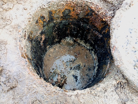 The open sewage well is full of waste from human life and food preparation. City sewerage and drainage system cleaning.
