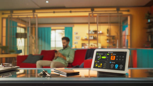 istock Creative Smart Home Device with Infographics Shown on Display. In the Background Person using Smartphone to Control His stylish House. Concept of IOT High-Tech Connected Wireless Intelligent System 2140494193