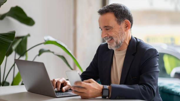 istock Engaged senior businessman multitasking with a laptop and smartphone 2140502284