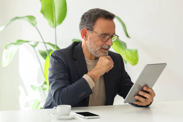 istock Thoughtful mature man with glasses, dressed in a smart navy jacket and beige sweater 2140503380