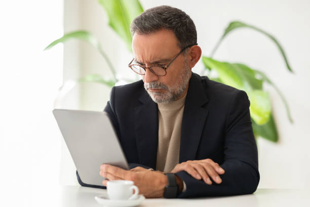istock Concentrated senior businessman with eyeglasses focused on a digital tablet screen 2140503381