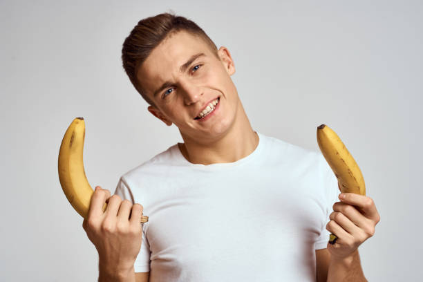 istock guy with a banana in his hand on a light background fun emotions light background white t-shirt model 2140503402