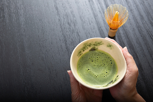 Hand holding matcha, white matcha tea bowl