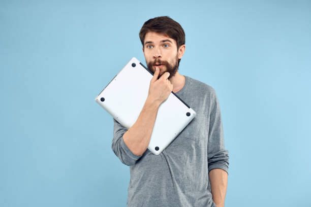 Millennial professional using laptop outdoors for fast, on-the-move business updates near corporate headquarters -  smart workflow, mobile business, and tech-savvy entrepreneur