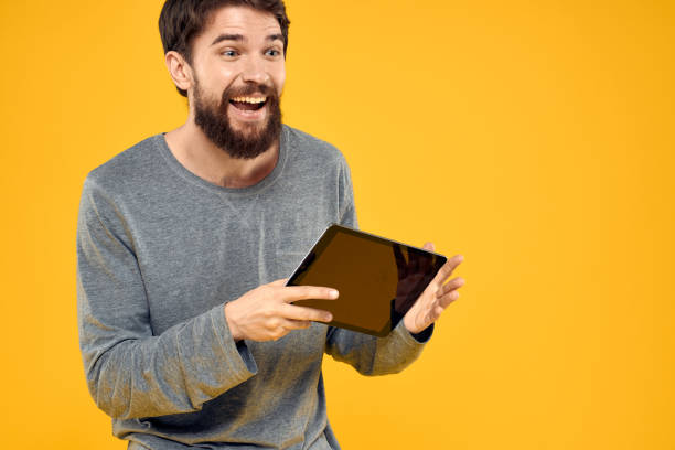 istock Emotional man with tablet in hands technology internet device lifestyle yellow background 2140538913