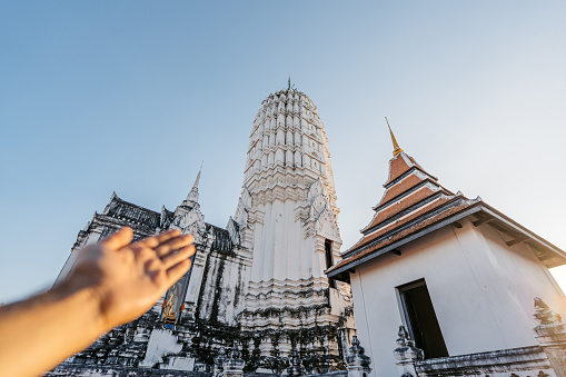 Young man's hand showing Wat Phutthaisawan in Ayutthaya historical park in Ayutthaya in Thailand.