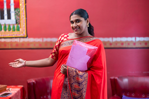 Confident Indian woman in traditional saree holding educational materials, ready to present.