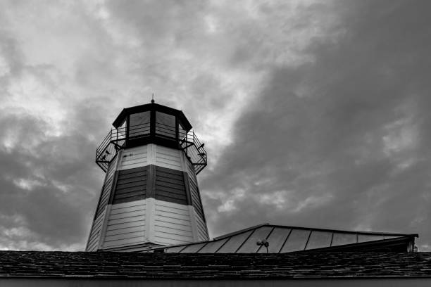 A monochrome shot of a tall lighthouse under an overcast sky.