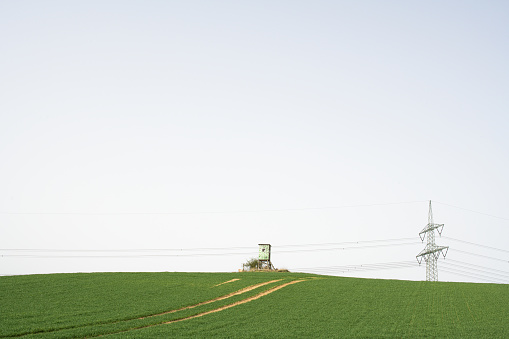 Spring Landscape in Mecklenburg-Vorpommern, Agricultural field with Power line  and hunting blind