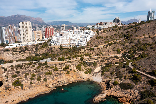 Aerial drone photo or the north part of Benidorm in Spain showing the rocky paths by the ocean in the summer time and the beach known as The Cala Tio Ximo Beach