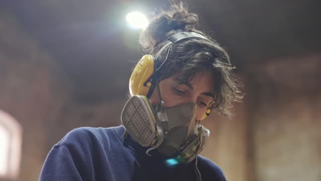 Carpenter respirator. Woman in noise canceling headphones. Protective dust mask.