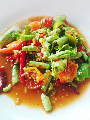 close up som tum or yard long bean salad with tomato and chili
