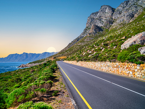 Winding road R44 along indian ocan with lush bush and rugged mountain at Kogel Bay, Cape Town, South Africa