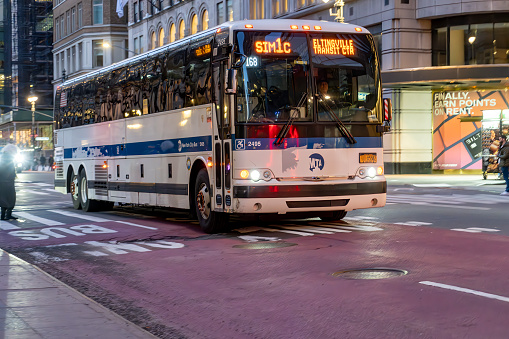Manhattan, New York, USA - March, 2024. A bus driving along a Manhattan street at night.