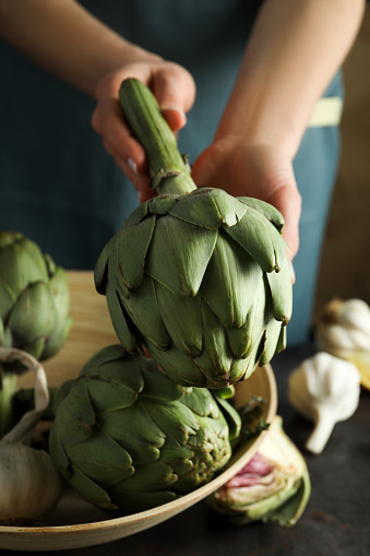 Two artichokes. The plant in the foreground is cut in half to display the artichoke heart. The vegetable flower in the background is whole. Shown on a white background. This food may be grown on an organic farm and is an ingredient for gourmet meals. It may be part of a vegetarian diet.