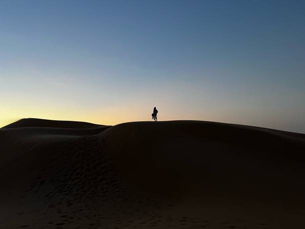 istock man on dunes silhouetted against sky at sunset, outdoors 2140619030